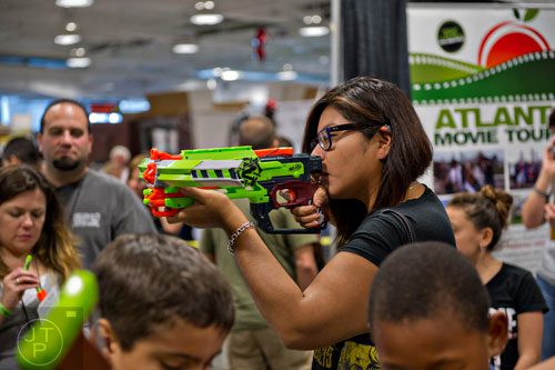 Brenda Huapaya (center) aims a NERF crossbow at targets during Walker Stalker Con in Atlanta on Sunday, October 19, 2014. 