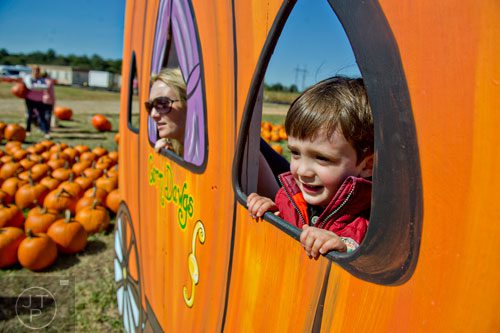Ryder McHughes (right) and his mother Jessica Mitchell stick their heads out of pumpkins as they pose for a photo at Corn Dawgs in Loganville on Sunday, October 5, 2014.