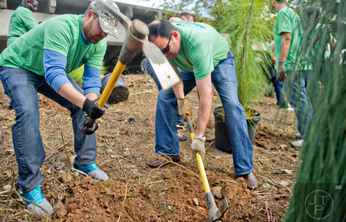 Brad Bollier (left) and Eric Broome use pick axes to break up dirt as they help plant 80 trees along the Atlanta Beltline on Wednesday, October 8, 2014. 