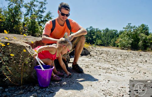 Ariannah Ganzhorn (left) puts rocks in her bucket as she takes a break from hiking Arabia Mountain in Lithonia with her father Chris on Wednesday, September 24, 2014.  
