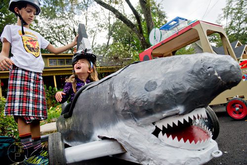 Jacob Donald (left) puts a shark fin helmet on Penelope Netherton's head as she sits in a fellow racers vehicle before the start of the 4th annual Madison Ave. Soap Box Derby in Decatur on Saturday, September 27, 2014.