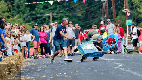 Rowan Wall (right) starts to flip as his father Chad rushes to his aid during the 4th annual Madison Ave. Soap Box Derby in Decatur on Saturday, September 27, 2014.