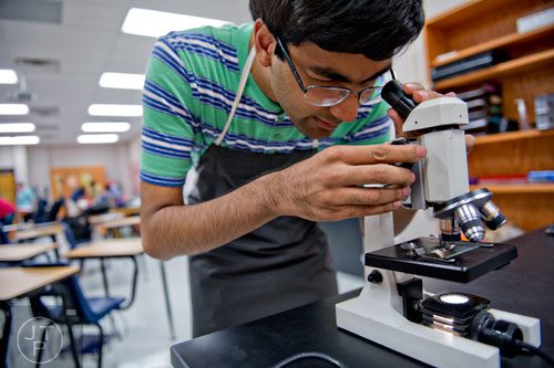 Haroon Alam looks through a microscope during a chemistry class at Walton High School on Tuesday, October 14, 2014. 