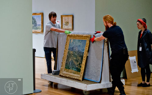 Ed Hill (left) and Tommy Sapp move Paul Cezanne's oil on canvas Mont Sainte-Victoire using a cart under the watchful eyes of project registrar Janet Hawkins before they hang it in the High Museum of Art's new "Cezanne and the Modern: Masterpieces of European Art from the Pearlman Collection" exhibit on Tuesday, October 14, 2014.  