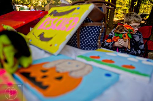 Avery Samples hugs his dachshund Hope as he works the table selling his sister's art during Howl-O-Weenie at Liane Levetan Park at Brook Run in Dunwoody on Saturday, October 4, 2014. 