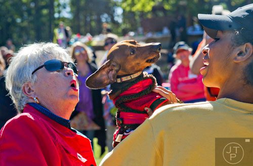 Amada Jones (right) and Jane Gleason (left) try to coax Jones' dachshund Charlie to howl during Howl-O-Weenie at Liane Levetan Park at Brook Run in Dunwoody on Saturday, October 4, 2014. 