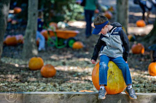 Evan Penrose sits on a pumpkin at Scottsdale Farms in Alpharetta as his family searches for a pumpkin for Halloween on Saturday, October 4, 2014.  