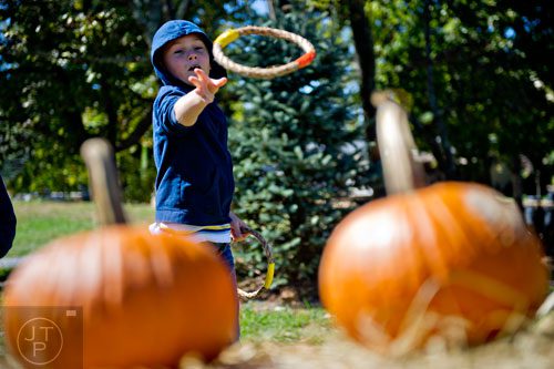 Michael Harper tries to toss a rope ring around a pumpkin at Scottsdale Farms in Alpharetta as his family searches for a pumpkin for Halloween on Saturday, October 4, 2014.  