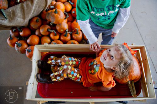 Harper Gillins (bottom) rests her head on a pumpkin as her cousin Jack Rogers pulls her around in a wagon at Kinsey Family Farm in Cumming on Saturday, October 4, 2014.  