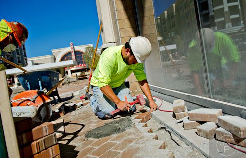 Jorge Alonzo (left) and Sergio Renoj install bricks on a sidewalk as construction continues at the new Avalon development in Alpharetta on Friday, October 17, 2014. 