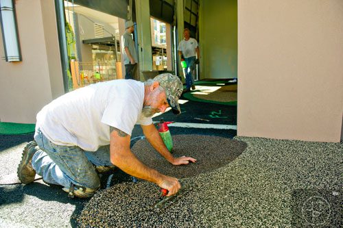 Glenn Gauthier spreads safety rubber surfacing inside one of the family zones at the new Avalon development in Alpharetta on Friday, October 17, 2014. 