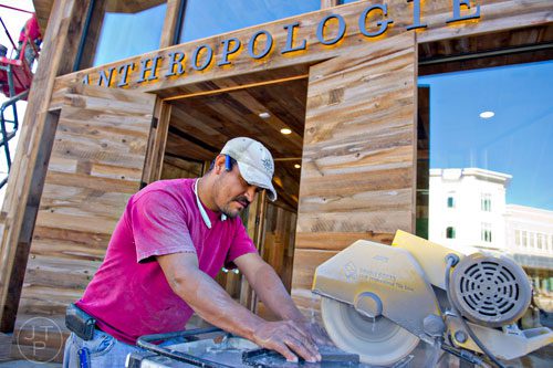 Roberto Lara uses a saw to cut tile in front of the Anthropologie store at the new Avalon development in Alpharetta on Friday, October 17, 2014. 