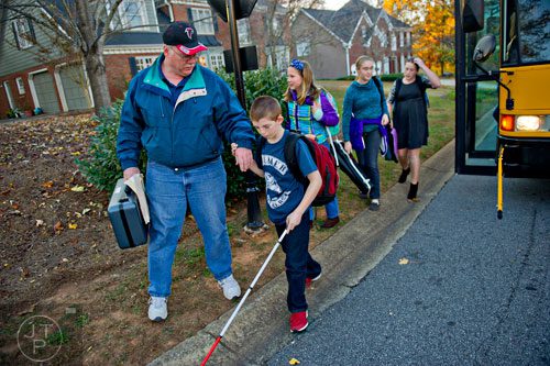 Christopher Abel (center) holds his father David's hand as they walk from the bus stop to their home in Acworth on Friday, November 14, 2014.