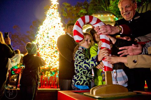 Cecily Sullivan (center) pushes the candy cane to turn on the lights on the main Christmas tree inside Six Flags Over Georgia in Austell on Friday, November 21, 2014. 