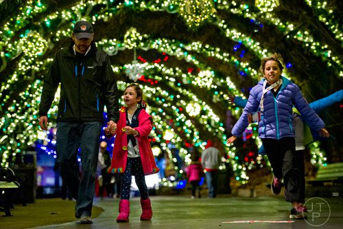 Rob Wentz (left) holds hands with his daughter Harper as Hailey Ingram runs past inside Six Flags Over Georgia in Austell on Friday, November 21, 2014.