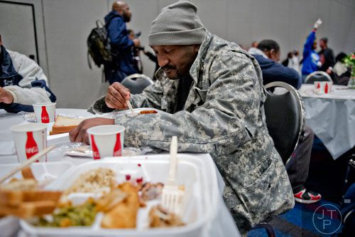 Louis McClure Jr. (center) takes a bite of his meal during the 44th annual Hosea Feed the Hungry and Homeless Thanksgiving Holiday Dinner at the Georgia World Congress Center in Atlanta on Thursday, November 27, 2014. 