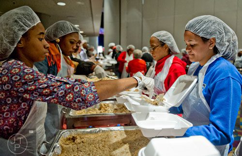 Kameron Austin (left) scoops a helping of stuffing onto a plate held by Allegra George during the 44th annual Hosea Feed the Hungry and Homeless Thanksgiving Holiday Dinner at the Georgia World Congress Center in Atlanta on Thursday, November 27, 2014. 
