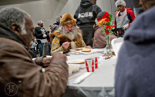 James Vesterfelt (center) takes a bite of his meal during the 44th annual Hosea Feed the Hungry and Homeless Thanksgiving Holiday Dinner at the Georgia World Congress Center in Atlanta on Thursday, November 27, 2014. 