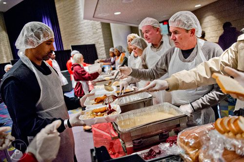 Benjamin Johnson (left) takes a plate through the serving line as Don Stepanek scoops on a helping of gravy during the 44th annual Hosea Feed the Hungry and Homeless Thanksgiving Holiday Dinner at the Georgia World Congress Center in Atlanta on Thursday, November 27, 2014. 