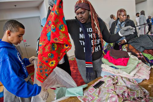 M.J. Fils (left) holds a bag open for Erica Fields as she puts in a piece of clothing during the 44th annual Hosea Feed the Hungry and Homeless Thanksgiving Holiday Dinner at the Georgia World Congress Center in Atlanta on Thursday, November 27, 2014. 