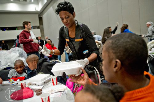 Kimberly Newman (center) hands a plate of food to April Cloud during the 44th annual Hosea Feed the Hungry and Homeless Thanksgiving Holiday Dinner at the Georgia World Congress Center in Atlanta on Thursday, November 27, 2014. 