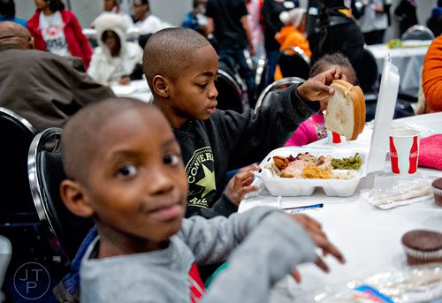 Tyshyne Bryant (center) and Quindarious Tillman dig into their meals during the 44th annual Hosea Feed the Hungry and Homeless Thanksgiving Holiday Dinner at the Georgia World Congress Center in Atlanta on Thursday, November 27, 2014. 