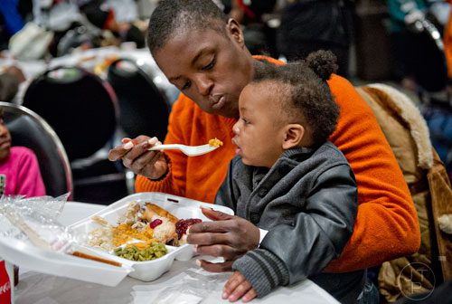 April Cloud (center) helps feed eleven-month-old Malik Smith during the 44th annual Hosea Feed the Hungry and Homeless Thanksgiving Holiday Dinner at the Georgia World Congress Center in Atlanta on Thursday, November 27, 2014. 