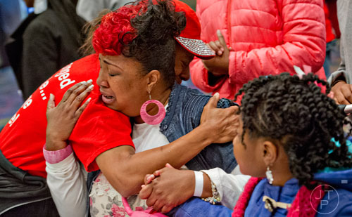 Angela Range (center) cries as she is hugged by Tecla Sanders (left) while they pray with Range's daughter Angel Alexander during the 44th annual Hosea Feed the Hungry and Homeless Thanksgiving Holiday Dinner at the Georgia World Congress Center in Atlanta on Thursday, November 27, 2014.