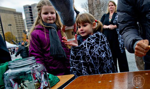 Natalie Taylor (right) is handed a cup of hot chocolate as she and Ella Bohntinsky wait for the start of the annual Macy's Great Tree Lighting celebration at Lenox Square Mall in Atlanta on Thursday, November 27, 2014. 