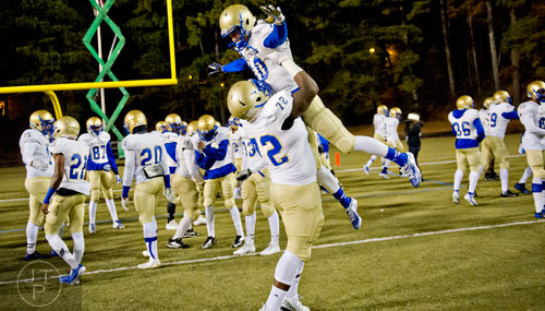 McEachern's Chandler Jones (72) lifts quarterback Bailey Hockman (10) into the air before their game against Tucker on Friday, November 28, 2014. 