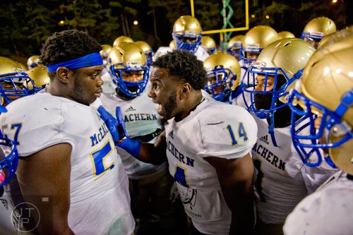 McEachern's Greg Austin (57) and DaMarcus Morgan (14) get their teammates pumped in a huddle before their game against Tucker on Friday, November 28, 2014. 