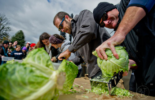 Scott Goggans (right), Dave French and other participants shred cabbage in a competition during the 12th annual Cabbagetown Chomp & Stomp in Atlanta on Saturday, November 1, 2014.