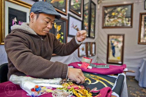 Don Tran pulls a silk thread as he hand sews a new work of art during the Chastain Park Art Festival in Atlanta on Sunday, November 2, 2014. 