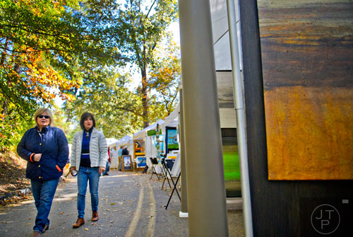 Mary Beth Bickes (left) and Suzy Berliner walk past artist booths during the Chastain Park Art Festival in Atlanta on Sunday, November 2, 2014.