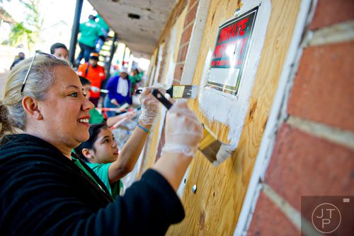 Amy Rodriguez (left) and her daughter Arianna paint over boarded up windows and doors at the Jett St. Apartments in Atlanta on Tuesday, November 4, 2014. 
