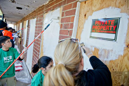 Aramys Rodriguez (left), his sister Arianna and mother Amy paint over boarded up windows and doors at the Jett St. Apartments in Atlanta on Tuesday, November 4, 2014. 