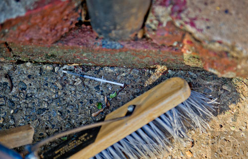 A hypodermic needle is swept away as volunteers help clean up the Jett St. Apartments in Atlanta on Tuesday, November 4, 2014. 