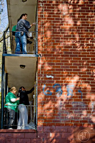 Shan Jenkins (top), Donna Mullis (bottom left) and Michelle Green paint boarded up windows and doors at the Jett St. Apartments in Atlanta on Tuesday, November 4, 2014. 