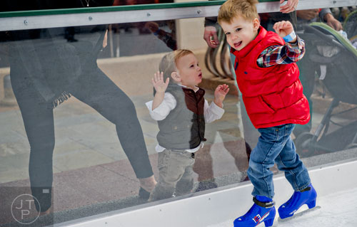 Barrett Pope (left) watches his older brother Wyatt skate on the ice rink at Avalon in Alpharetta on Sunday, November 30, 2014. 
