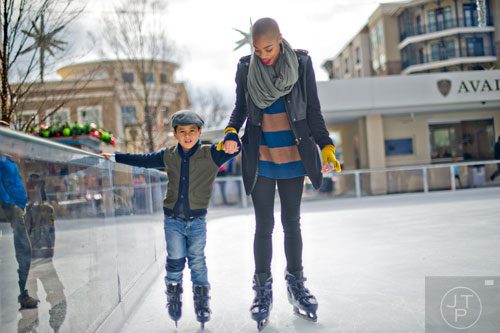 Kai Kapadia (left) holds hands with his cousin Szannlee Dickenson as they skate on the ice rink at Avalon in Alpharetta on Sunday, November 30, 2014. 
