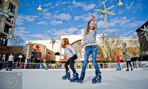Abby Ostwald (right) and Emma Seher skate on the ice rink at Avalon in Alpharetta on Sunday, November 30, 2014.