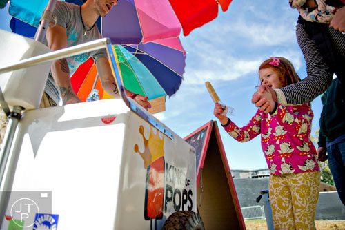Winifred Daly (center) is handed a popsicle from Cooper Creel as she holds her mother Elizabeth's hand during the 4th annual King of Pops Field Day at The Masquerade in Atlanta on Saturday, November 8, 2014. 