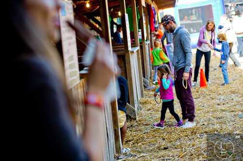 Tim Adkins (right) helps his daughter Harper Adkins-Bernstein play a ring toss game during the 4th annual King of Pops Field Day at The Masquerade in Atlanta on Saturday, November 8, 2014. 
