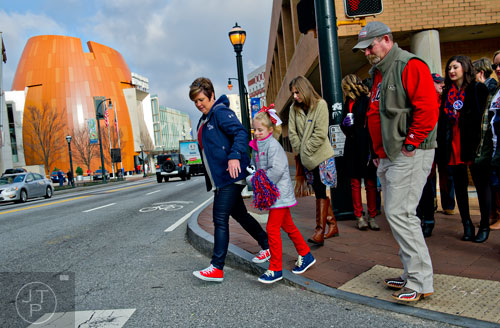 Charla Hodges (left) reaches for her niece Avery Thomas' hand as they cross Marietta St. in front of the College Football Hall of Fame on their way to watch the Chick-fil-A Peach Bowl at the Georgia Dome in Atlanta on Wednesday, December 31, 2014. 