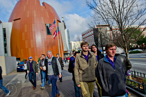 Drew Hershman (right), Tommy Bruhn and other fans pass by the College Football Hall of Fame on their way to watch the Chick-fil-A Peach Bowl at the Georgia Dome in Atlanta on Wednesday, December 31, 2014. 