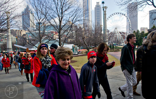 Tasha Grace (left), Marilyn Carrithers and Grace's son Riley walk through Centennial Olympic Park in Atlanta with thousands of other people to watch the Chick-fil-A Peach Bowl at the Georgia Dome on Wednesday, December 31, 2014. 