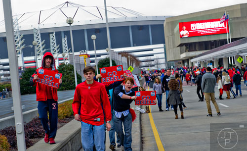 Brett Horner (left), Casey Cagle and Noah Hancock cheer for Ole Miss as thousands of people walk towards the Georgia Dome in Atlanta to watch the Chick-fil-A Peach Bowl on Wednesday, December 31, 2014. 