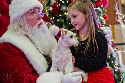 Milo (center), a maltese, looks around as Piper Smith visits with Santa at Town Center at Cobb in Kennesaw on Sunday, November 30, 2014.