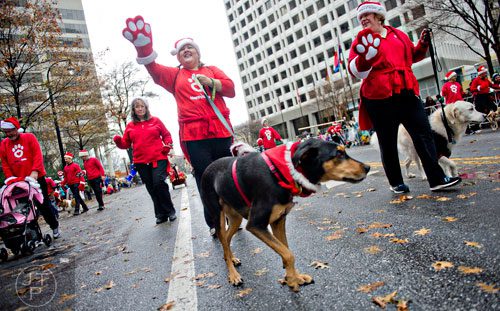 Laura Finnell (center) waves to the crowd as she walks down Peachtree St. with her dog Princess during the 2014 Children's Christmas Parade in Atlanta on Saturday, December 6, 2014. 