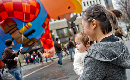 Held by her mother Chau Jones (right), Clu watches as balloons pass by during the 2014 Children's Christmas Parade in Atlanta on Saturday, December 6, 2014. 